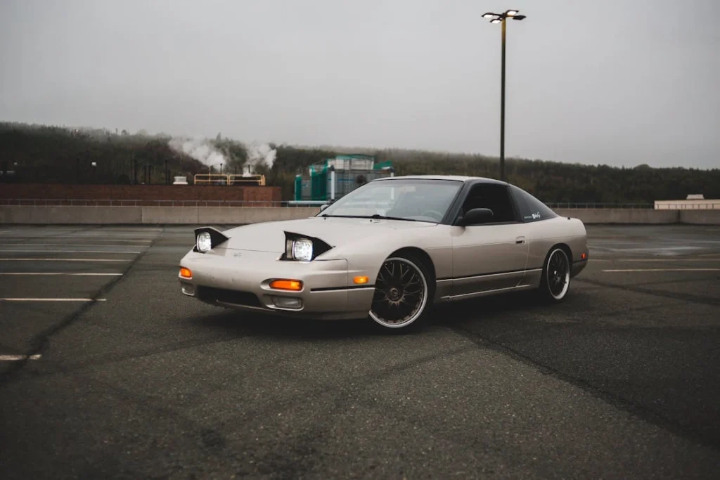 A sleek sports car with pop-up headlights parked in an urban setting during a foggy day