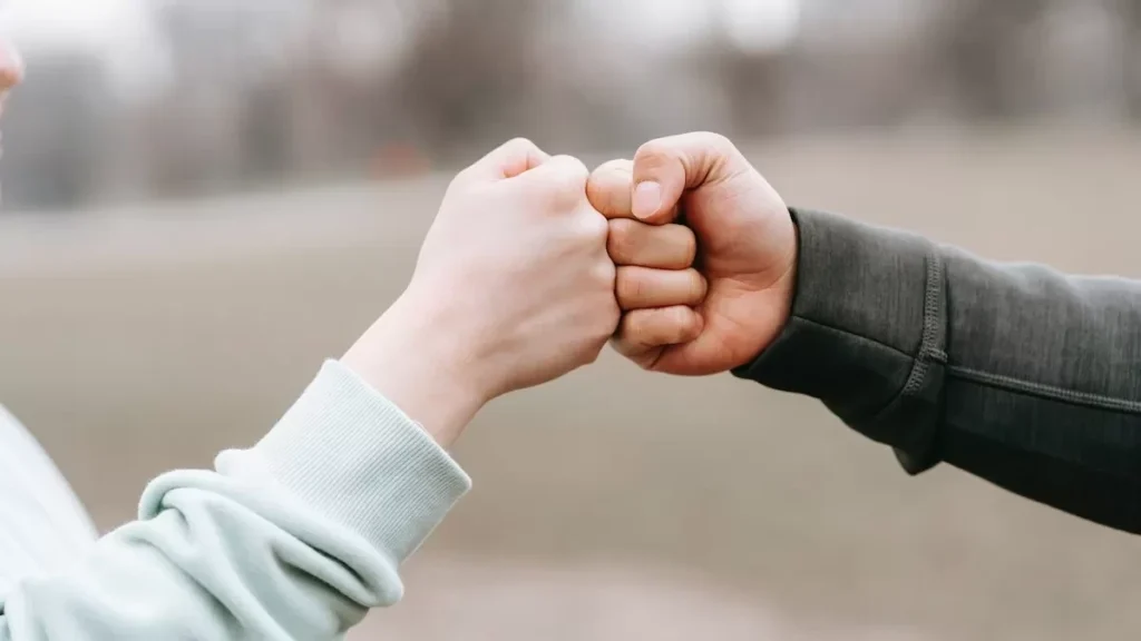 Two people engage in a friendly fist bump outdoors, symbolizing unity and friendship