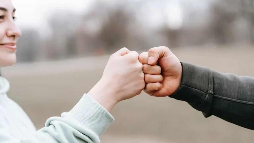 Two people engage in a friendly fist bump outdoors, symbolizing unity and friendship