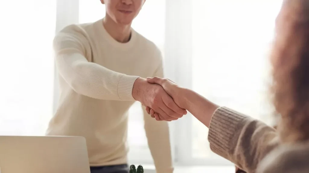 Close-up of professionals shaking hands over coffee in a modern office