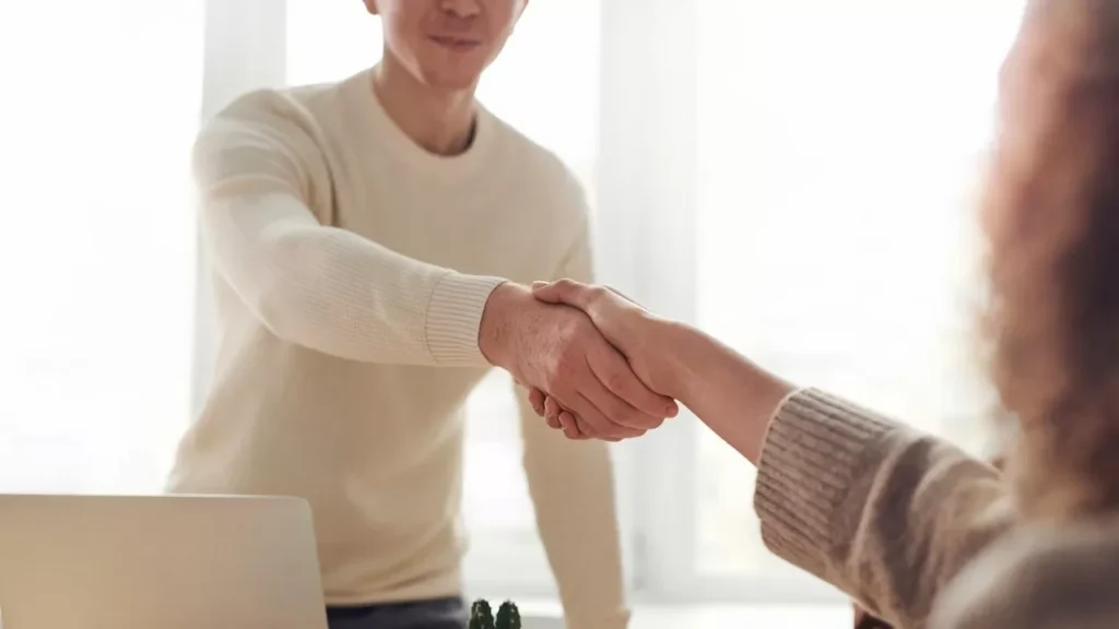 Close-up of professionals shaking hands over coffee in a modern office