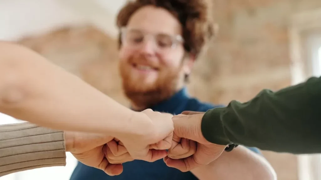 Group of diverse adults showing unity and teamwork with a fist bump indoors