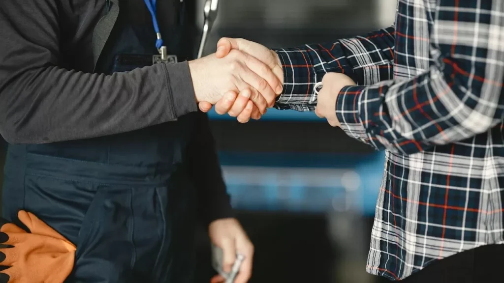 Close-up of a handshake between workers in a workshop, symbolizing business agreement and teamwork