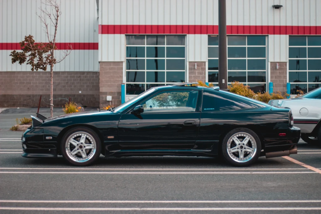 Black sports car parked in front of modern building with reflective windows, showcasing sleek design