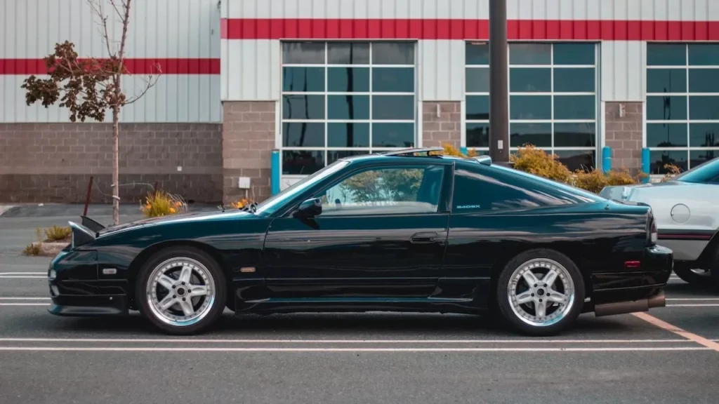 Black sports car parked in front of modern building with reflective windows, showcasing sleek design