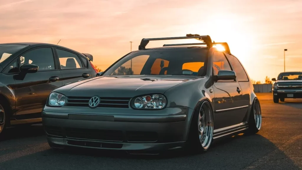 A modified Volkswagen car parked outdoors with a dramatic sunset backdrop