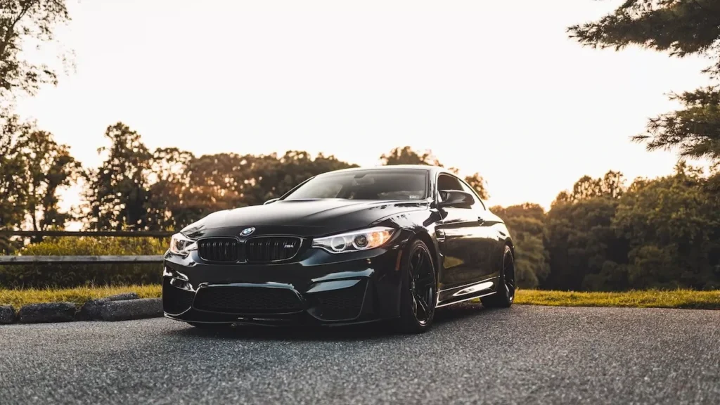 A stylish black car sits parked on a scenic road at sunset