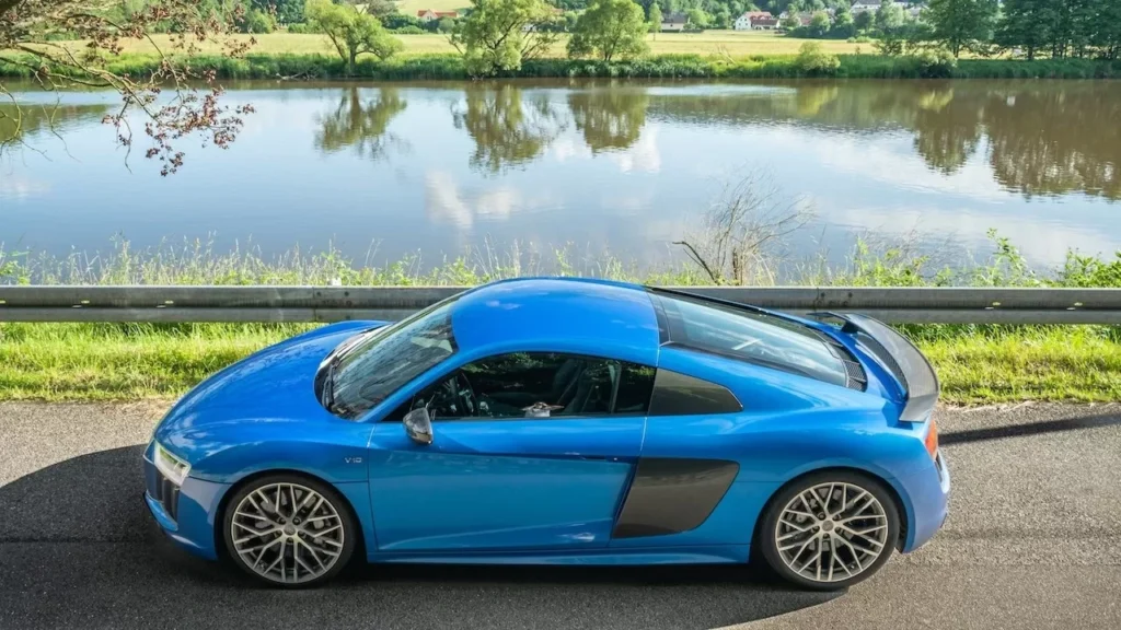 Striking blue sports car parked by a scenic river with lush countryside views