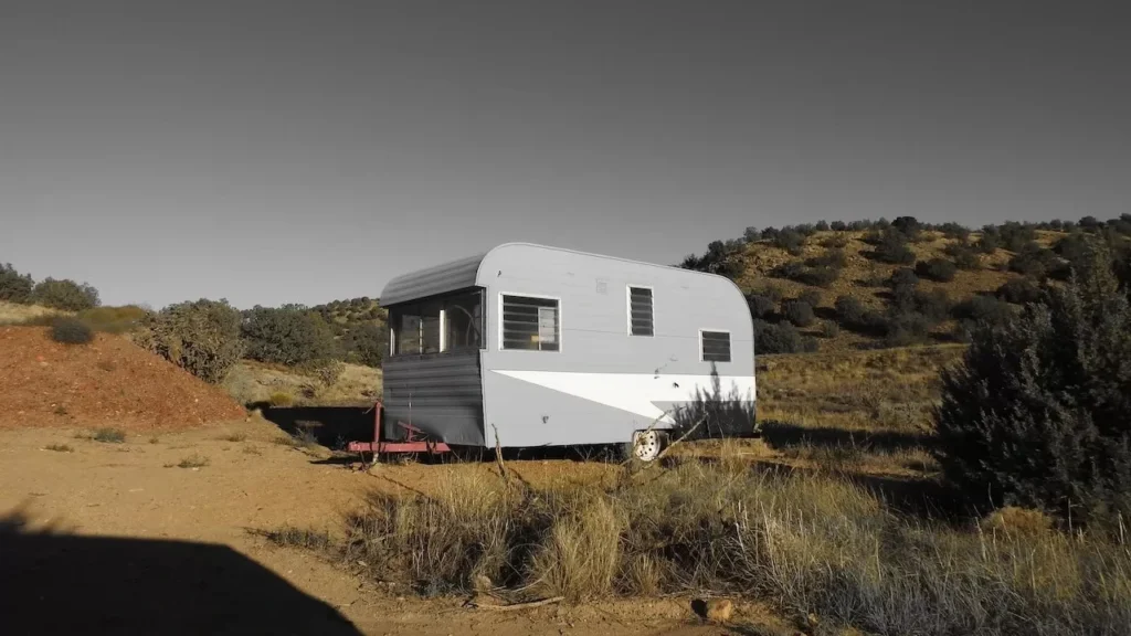 A vintage caravan parked in a serene desert setting under clear skies, perfect for travel enthusiasts