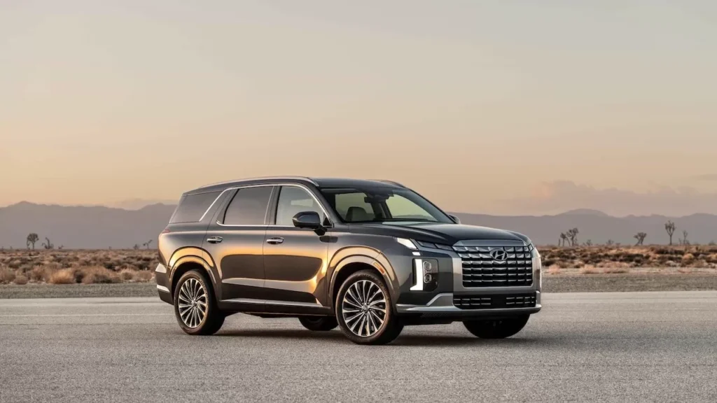 A sleek SUV parked on an empty road against a serene desert backdrop during sunset.
