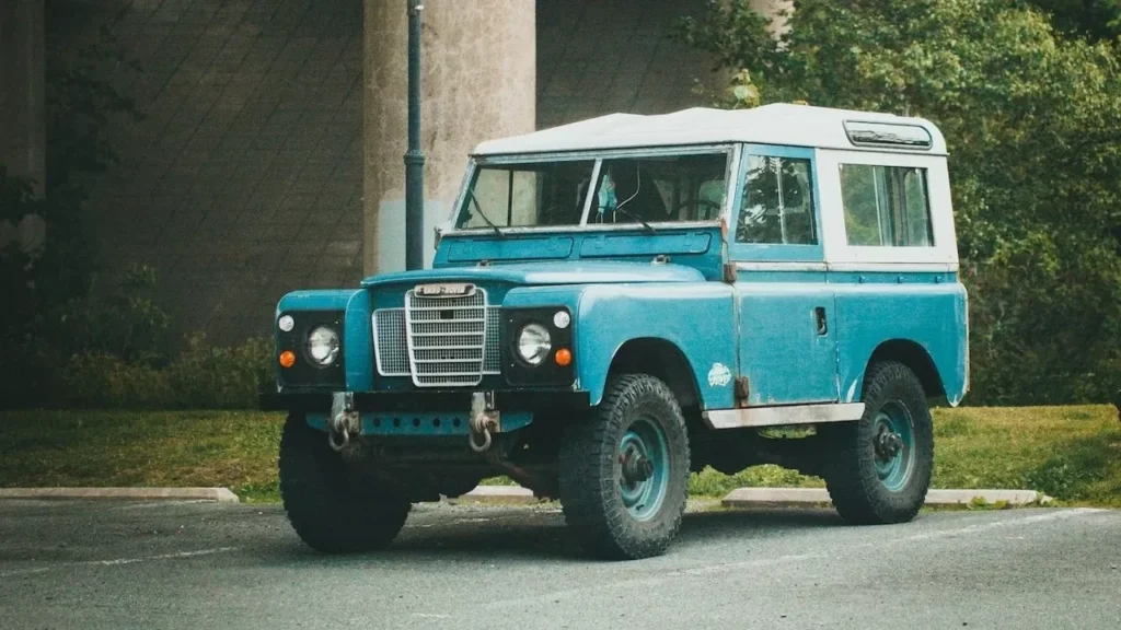 Classic blue Land Rover parked beneath a concrete bridge, surrounded by greenery
