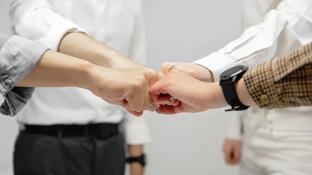 Close-up of diverse team members doing a fist bump indoors, symbolizing unity and teamwork