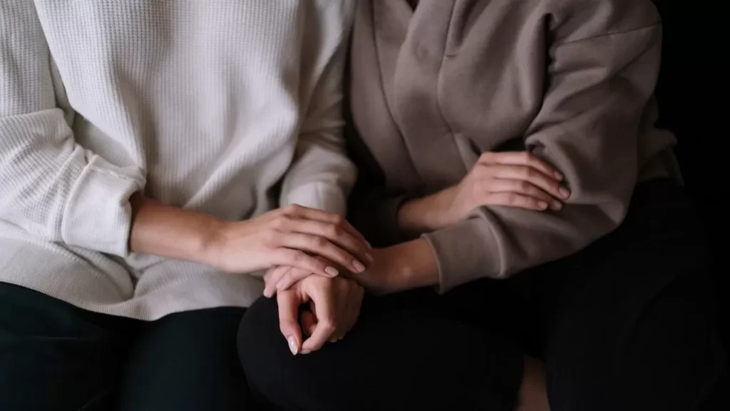 Two individuals sitting together, providing comfort and support with gentle touch