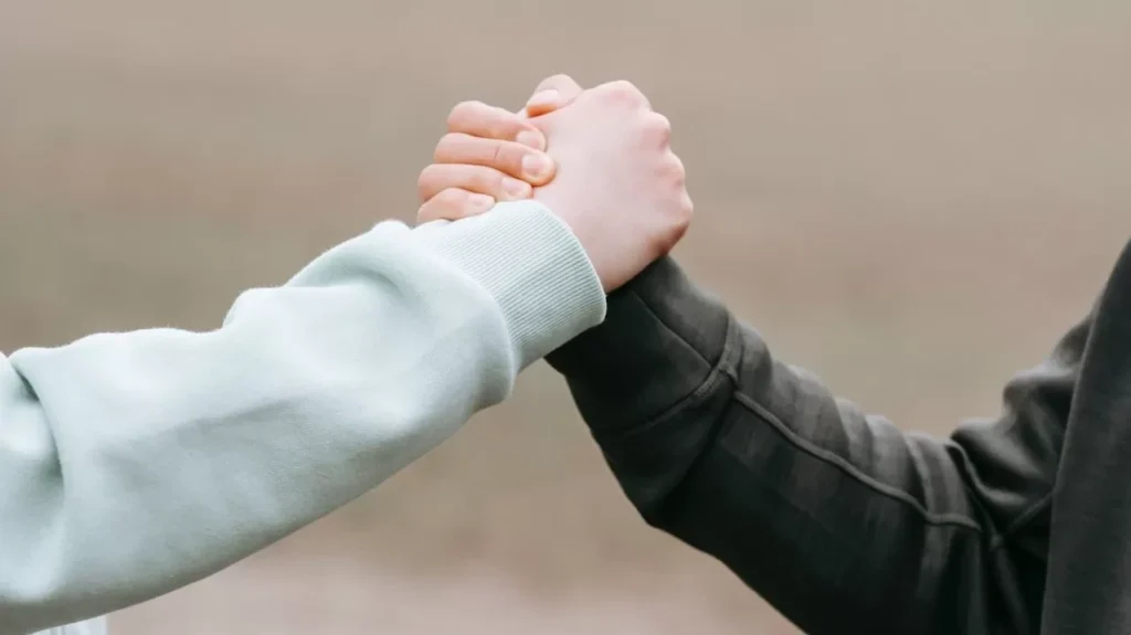 Two adults holding hands in an outdoor park setting, symbolizing trust and connection