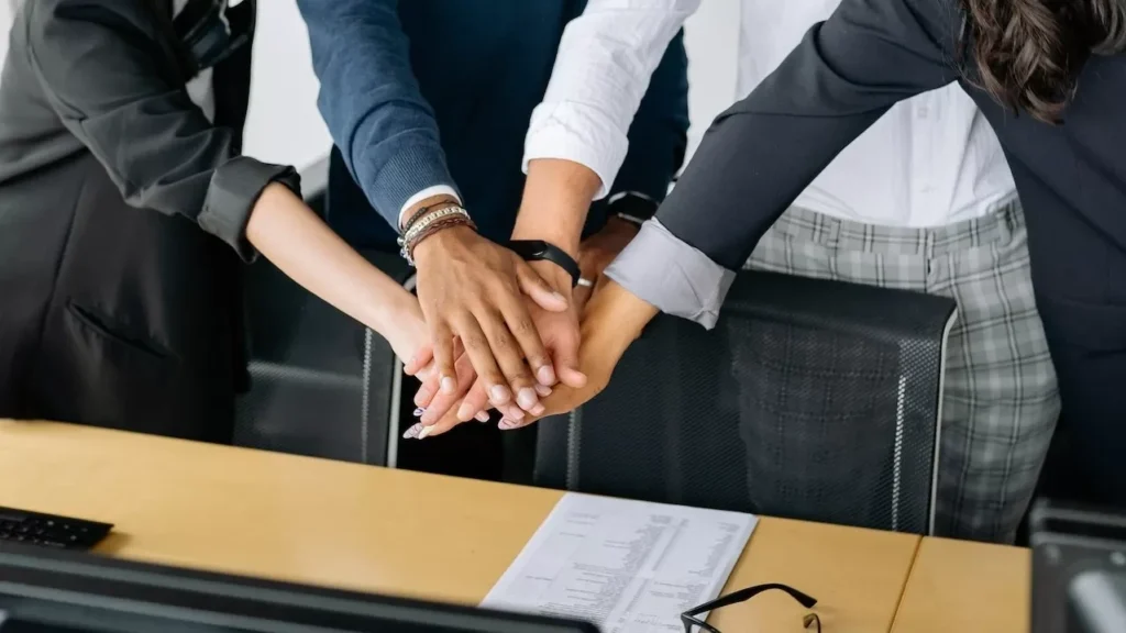 A close-up of a diverse business team stacking hands in unity, showcasing teamwork in an office setting.