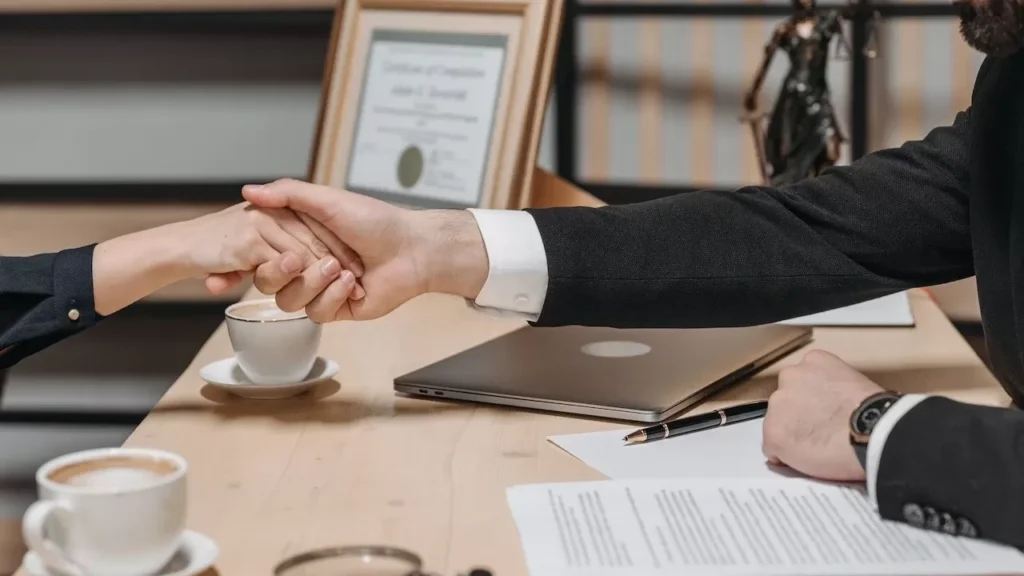 A formal handshake over a business contract in a corporate office setting
