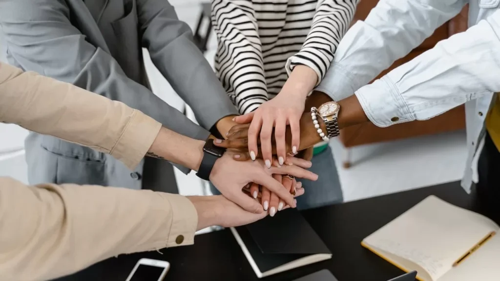A group of diverse colleagues joins hands in teamwork, symbolizing unity and collaboration