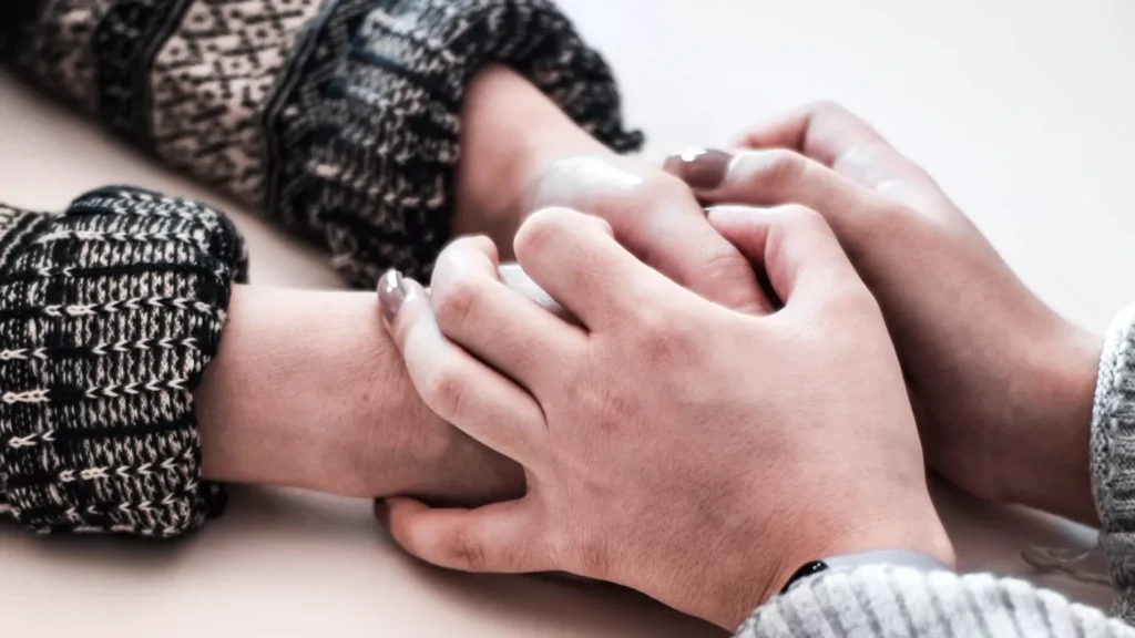Person in gray long sleeve shirt holding persons hand