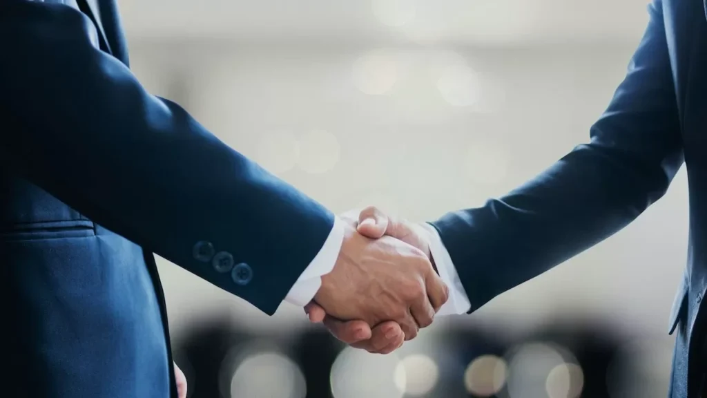 Close-up of business professionals in suits shaking hands, symbolizing a successful collaboration or agreement