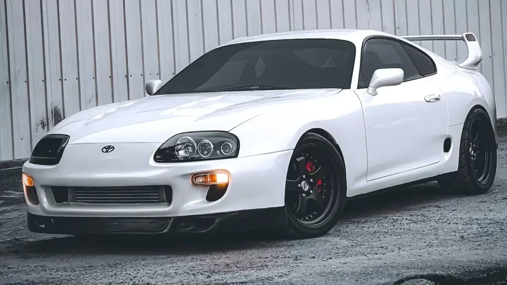 White sports car parked on pavement in front of industrial warehouse
