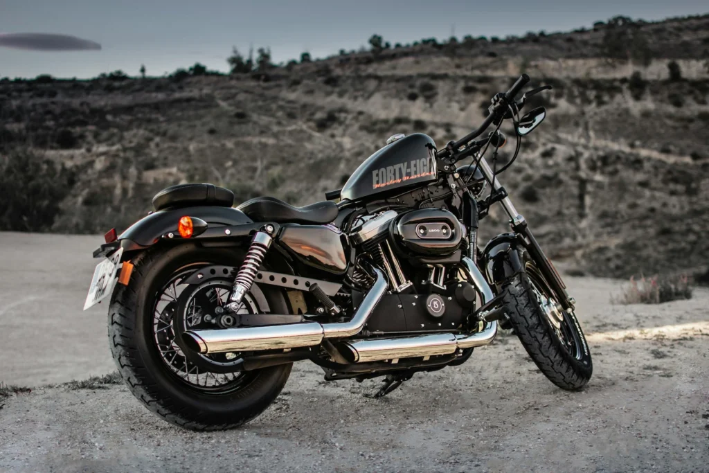 A parked Harley Davidson motorcycle on a gravel path with a scenic background