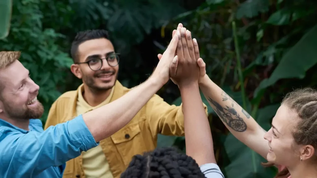 A joyful group of friends high-fiving outdoors
