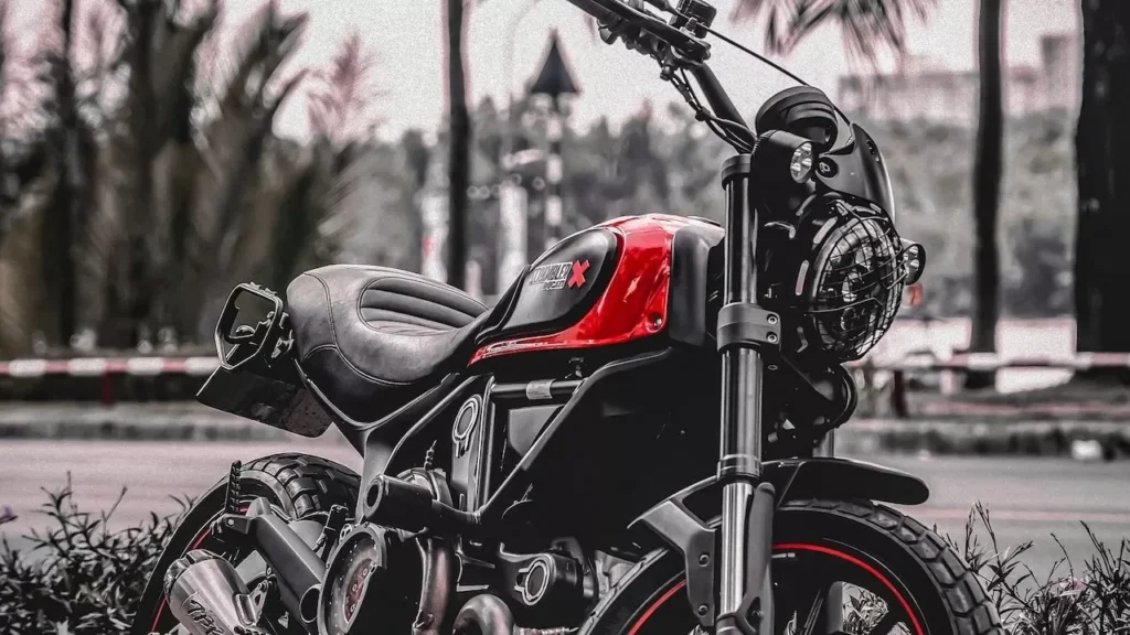 Dynamic image of a black and red sport motorcycle parked outdoors on a roadside