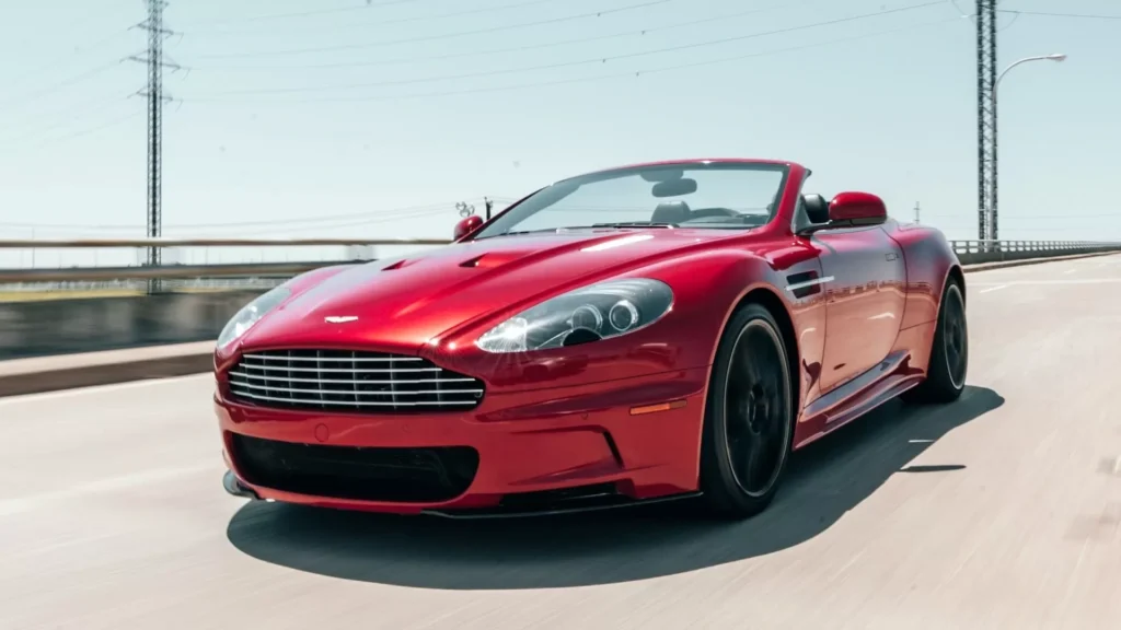 Red Aston Martin Vantage running on road