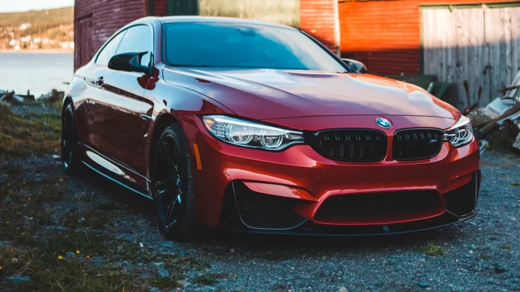 Red BMW m 3 parked near brown wooden building during daytime