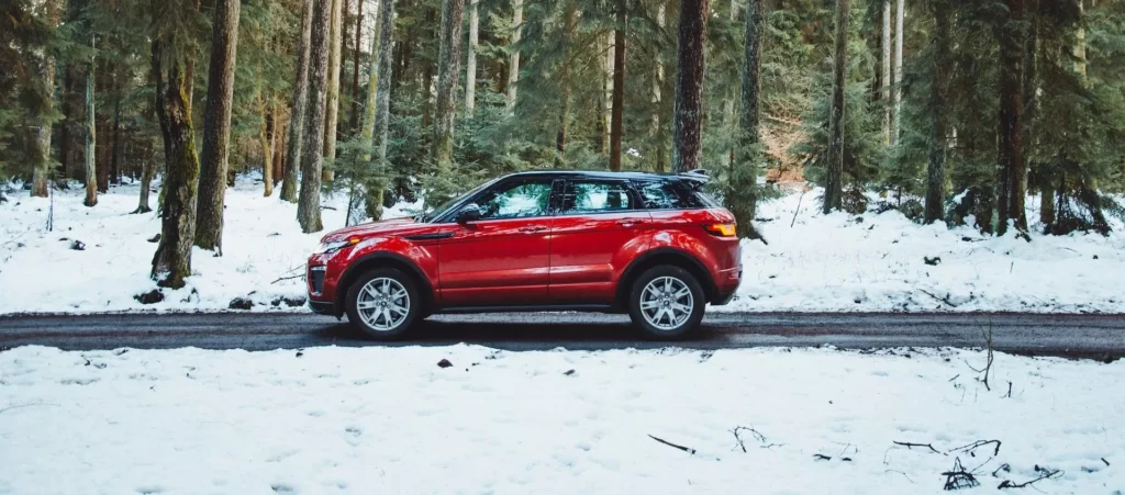 red suv on snow covered road during daytime