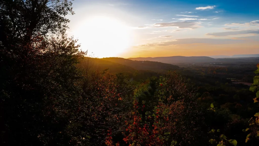 the sun is setting over the mountains and trees