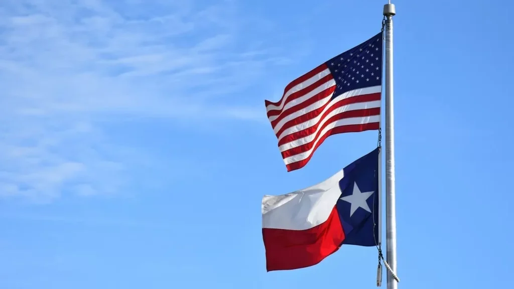 The United States Flag and Texas State Flag displayed blowing in the breeze against a beautiful Texas sky