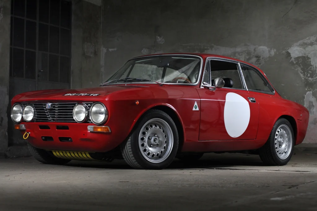 A stunning vintage red classic car parked indoors against an industrial backdrop