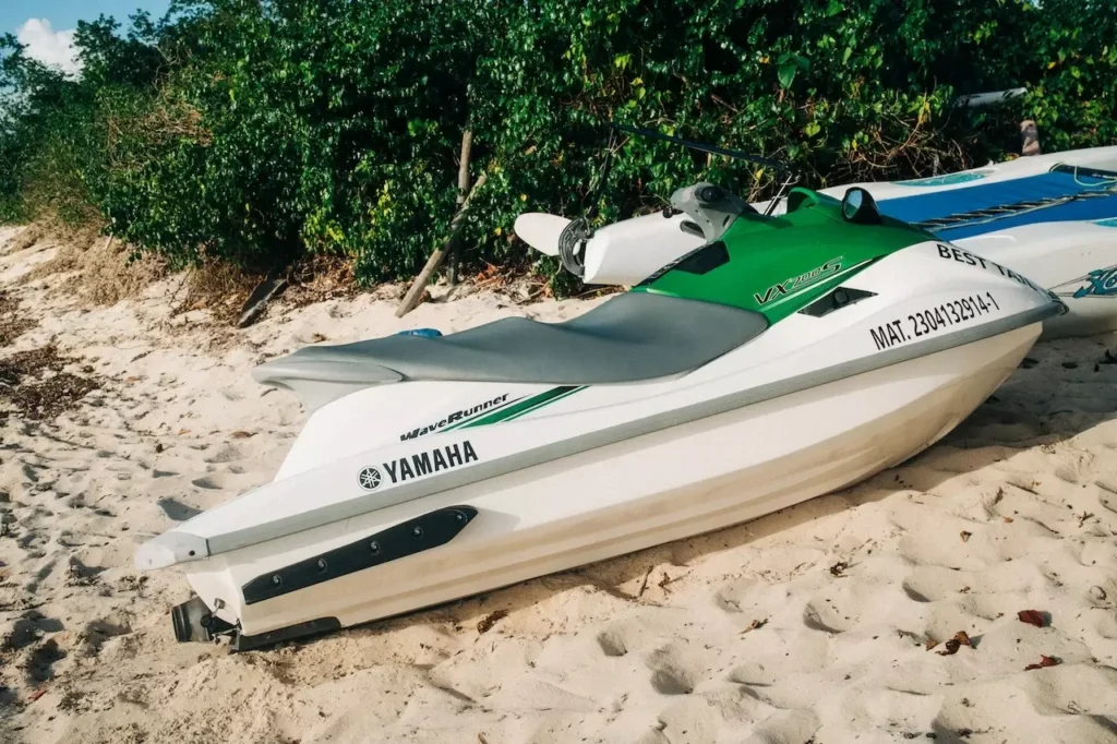 Jet skis parked on a sandy beach with lush tropical greenery in the background