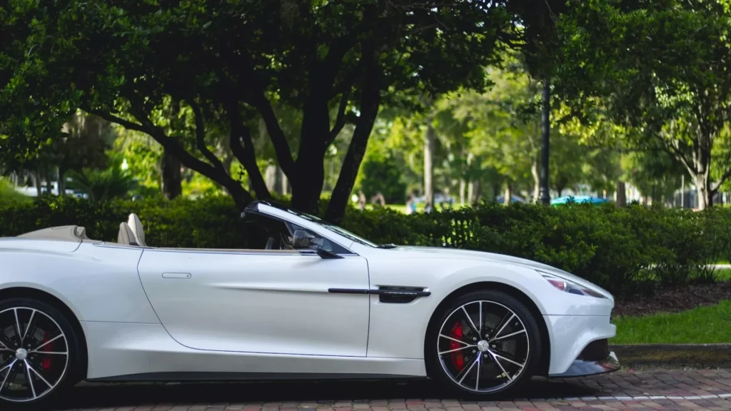 White Aston Martin convertible parked near trees