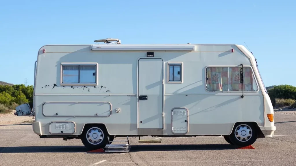 view of a vintage camper van parked on an open road under clear blue skies