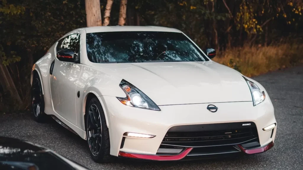 Close-up of a parked white sports car next to a black one on a forest road