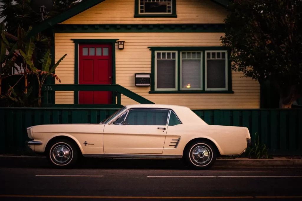White coupe parked in front of white and red house