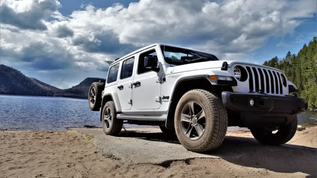 White Jeep parked by a scenic mountain lake under a dramatic cloudy sky