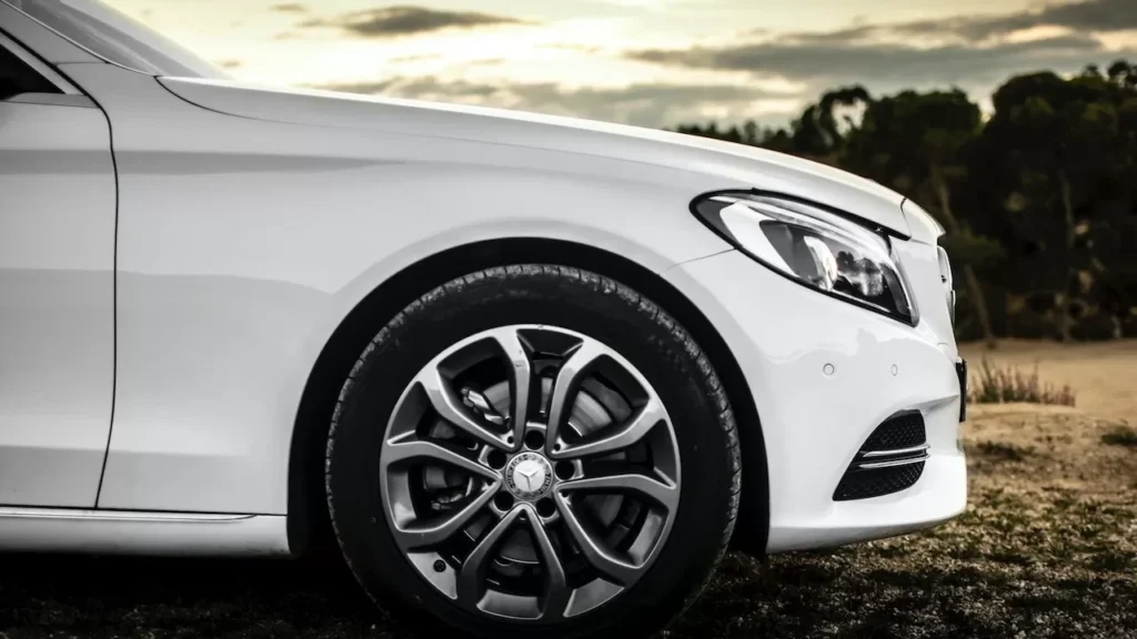 Close-up of a white car with stylish rims, captured outdoors in a serene setting