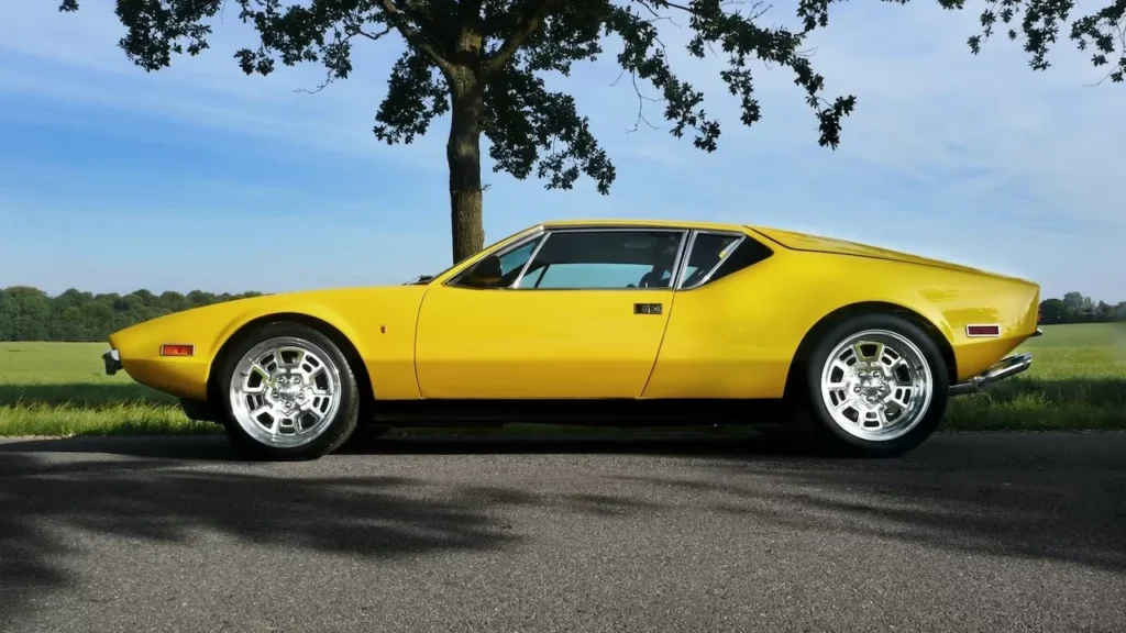 A vintage yellow convertible car parked on a sunny rural road, showcasing its classic design