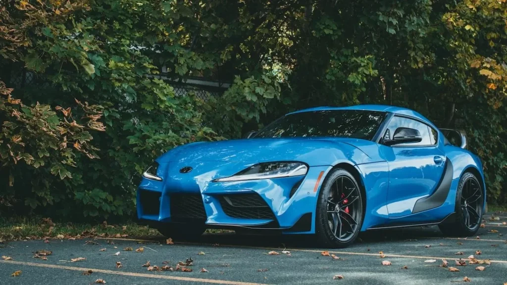 Luxurious blue sports car elegantly parked beside autumn foliage