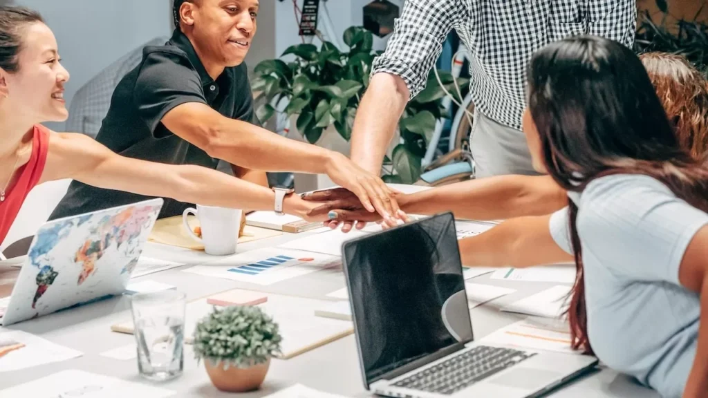A diverse group of colleagues in a meeting, stacking hands for teamwork