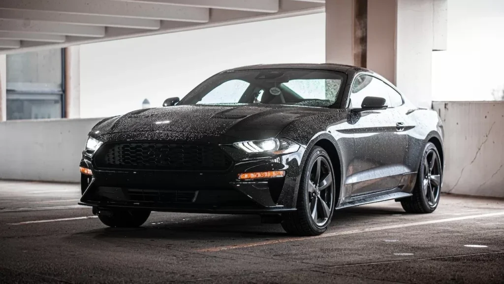 A sleek black Ford Mustang parked in a wet urban environment