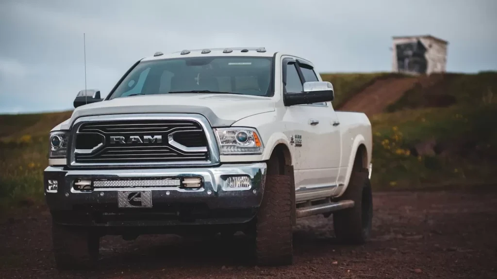 A modern white pickup truck parked on a dirt road in the countryside