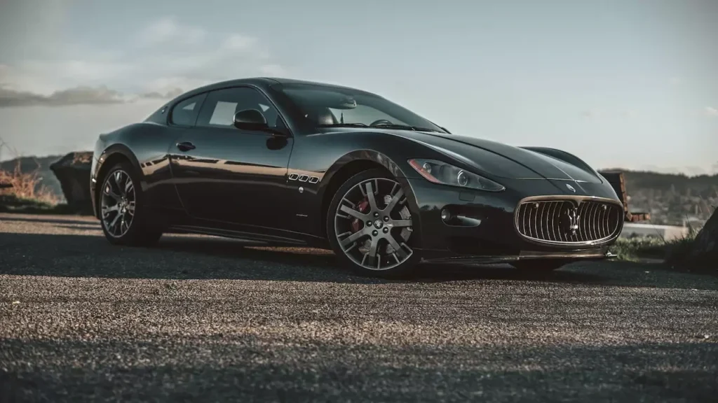 Luxurious black Maserati captured on an open road at sunset