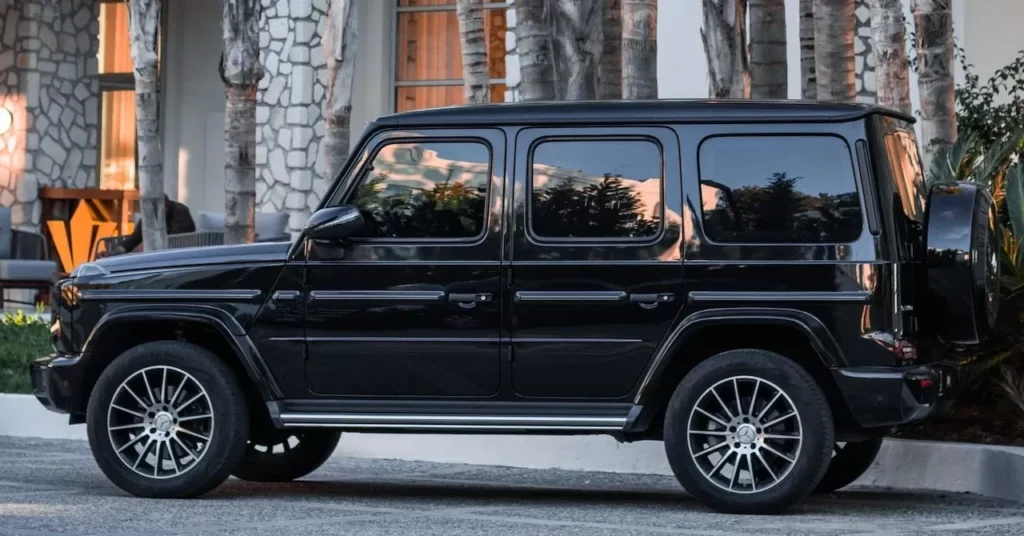 A sleek black luxury car parked outdoors near palm trees and a modern building