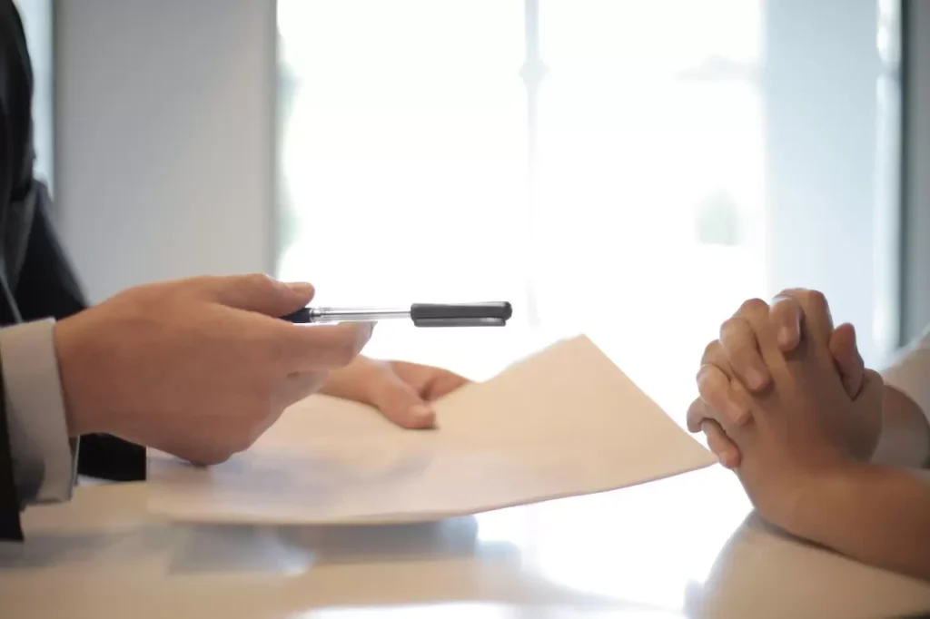 Close-up of a contract signing with hands over documents