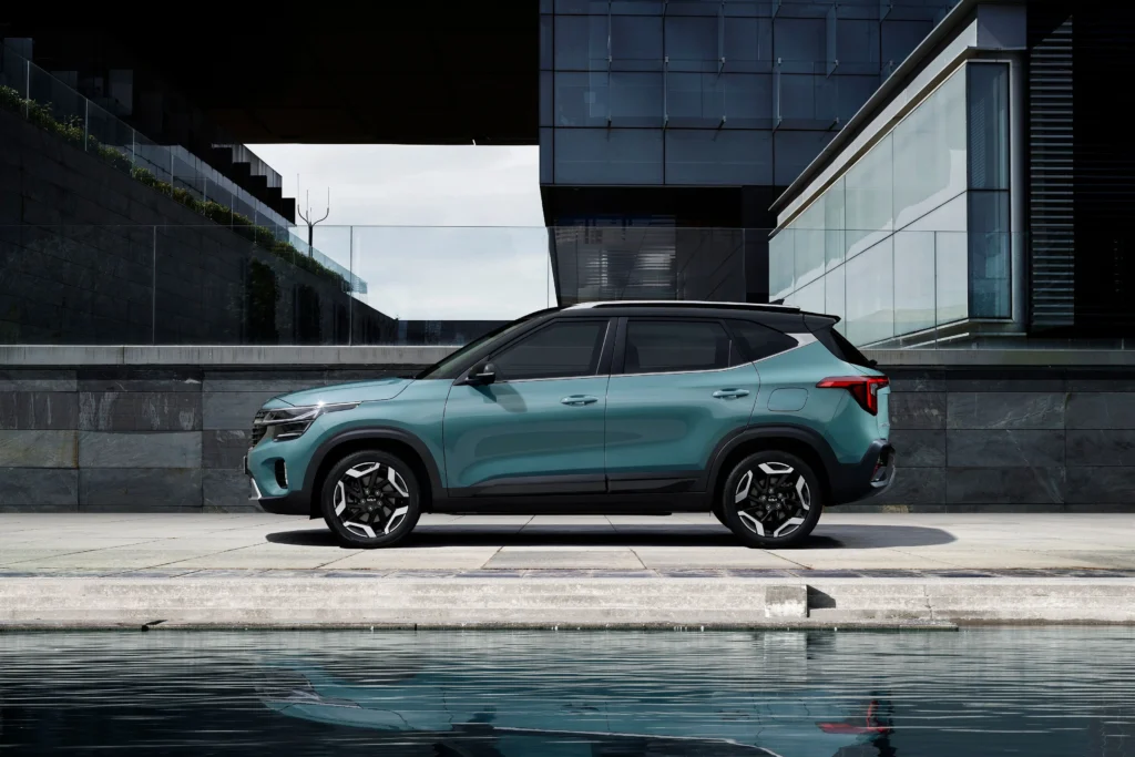 A sleek green SUV parked in front of a contemporary building beside a water feature
