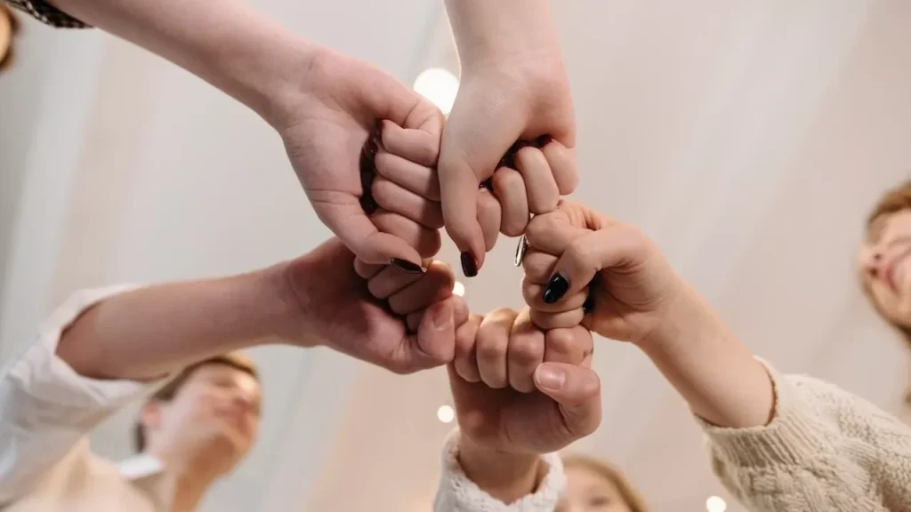 Close-up of a diverse group joining fists in a show of unity and teamwork indoors